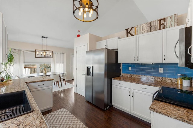 kitchen featuring a sink, backsplash, dark wood-style floors, appliances with stainless steel finishes, and an inviting chandelier