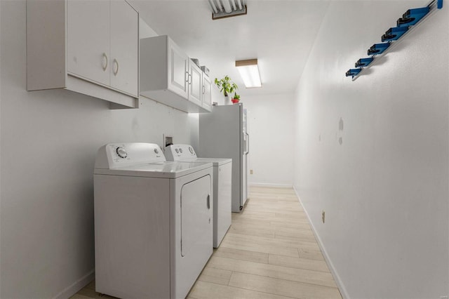 laundry area featuring baseboards, cabinet space, independent washer and dryer, and light wood-type flooring