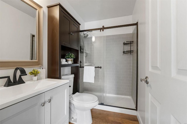 full bath featuring a stall shower, toilet, vanity, and wood finished floors