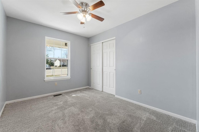 unfurnished bedroom with a ceiling fan, visible vents, carpet, baseboards, and a closet