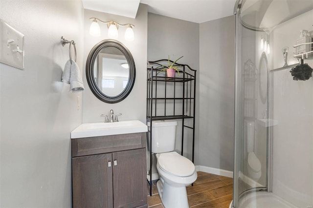 bathroom featuring a shower stall, baseboards, toilet, wood finished floors, and vanity