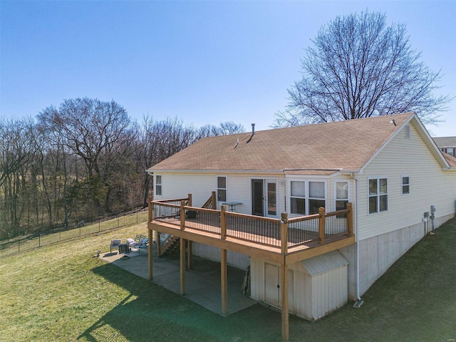 back of property with a lawn, a wooden deck, roof with shingles, and fence