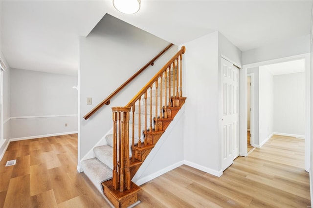 stairway featuring baseboards, visible vents, and wood finished floors