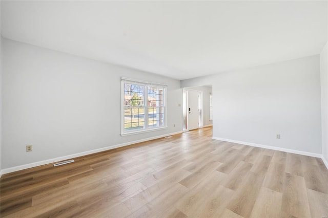 unfurnished room with light wood-type flooring, baseboards, and visible vents