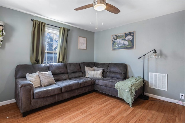 living room with light wood finished floors, baseboards, and visible vents