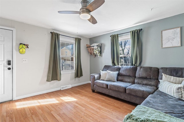 living room featuring a healthy amount of sunlight, visible vents, baseboards, and wood finished floors