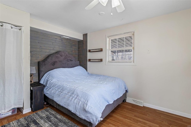 bedroom with baseboards, wood finished floors, visible vents, and a ceiling fan