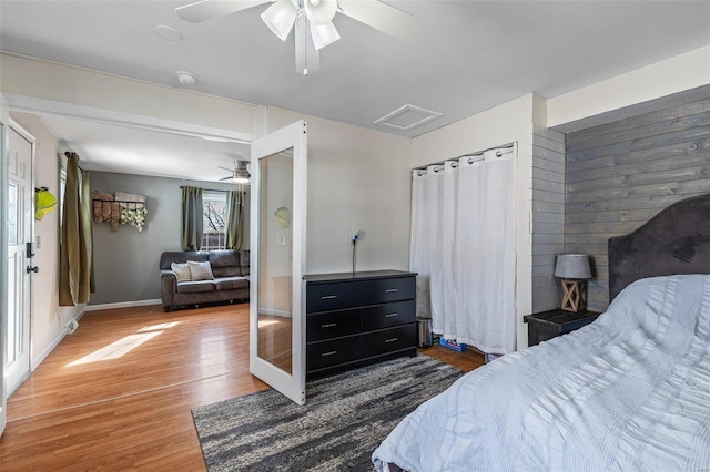 bedroom featuring ceiling fan, wood finished floors, attic access, and baseboards