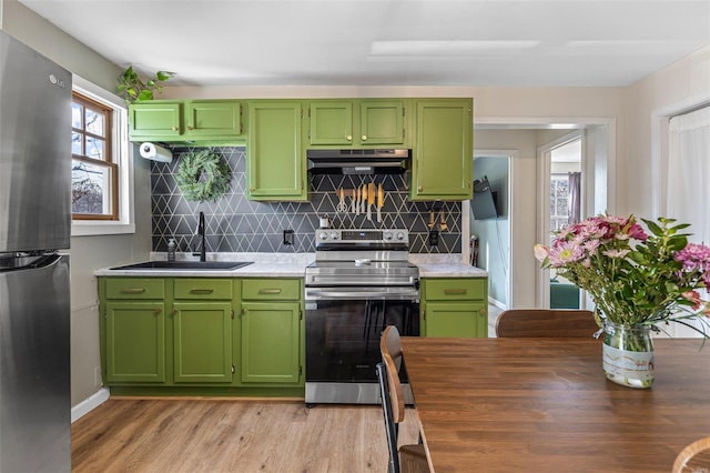 kitchen featuring under cabinet range hood, appliances with stainless steel finishes, light countertops, and a sink