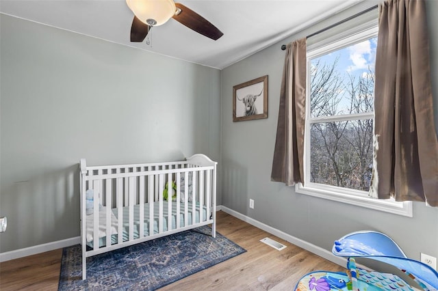 bedroom featuring multiple windows, wood finished floors, visible vents, and baseboards