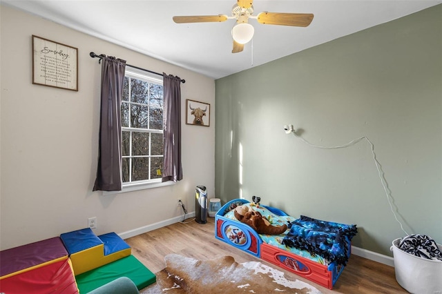 bedroom with ceiling fan, baseboards, and wood finished floors