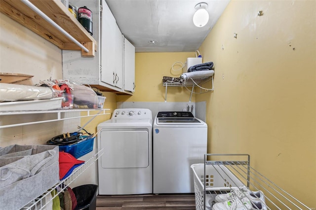 clothes washing area with dark wood-style floors, cabinet space, and washer and clothes dryer