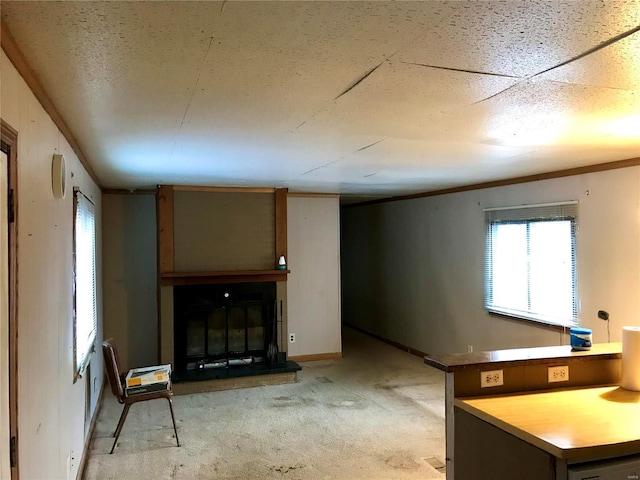 interior space featuring a glass covered fireplace, light carpet, crown molding, and baseboards