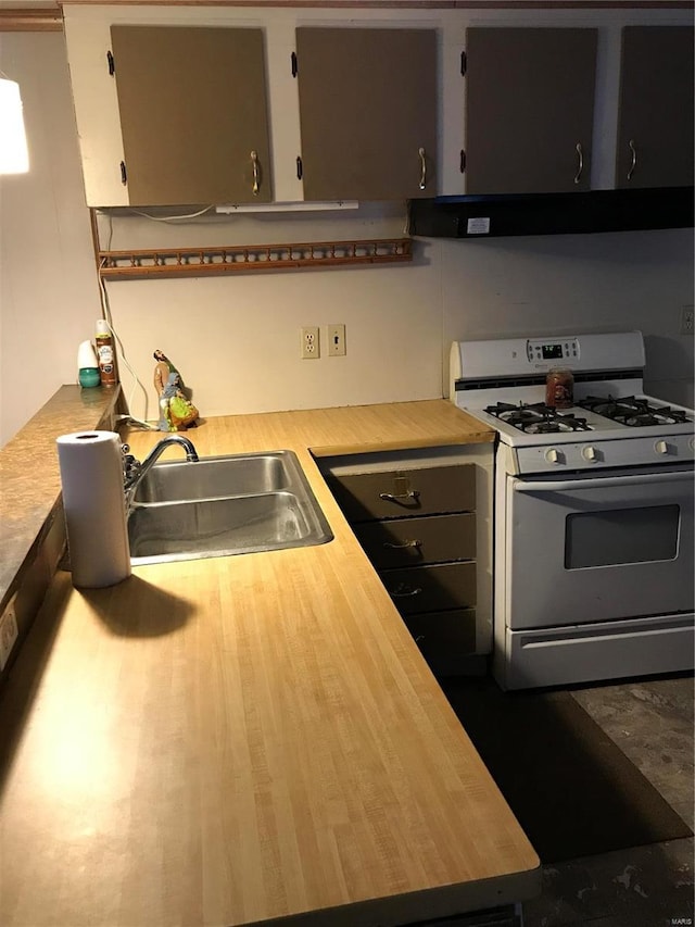 kitchen featuring white range with gas stovetop, light countertops, and a sink