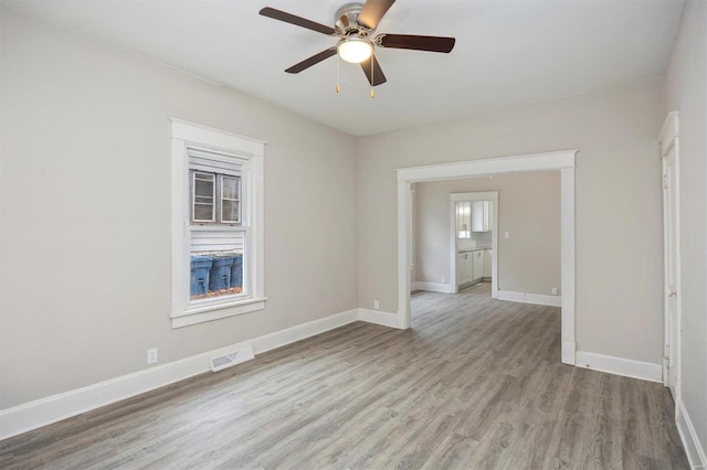 spare room featuring light wood-type flooring, visible vents, baseboards, and a ceiling fan