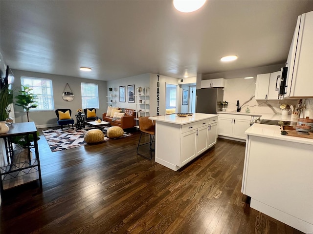 kitchen with dark wood-style floors, open floor plan, a center island, light countertops, and white cabinetry