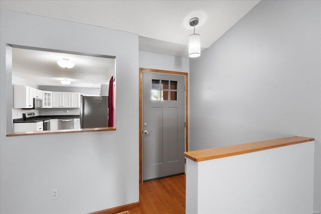 entrance foyer with a textured ceiling, baseboards, and wood finished floors