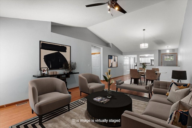 living room featuring lofted ceiling, visible vents, ceiling fan, wood finished floors, and baseboards