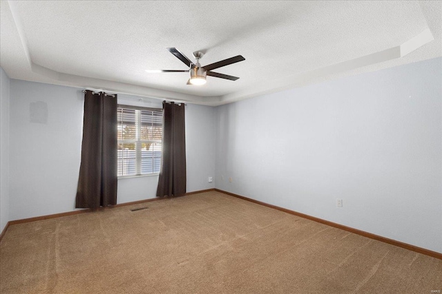 carpeted empty room with a ceiling fan, a textured ceiling, and baseboards