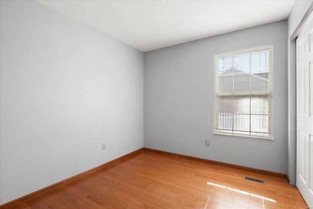 spare room with light wood-type flooring, baseboards, and visible vents