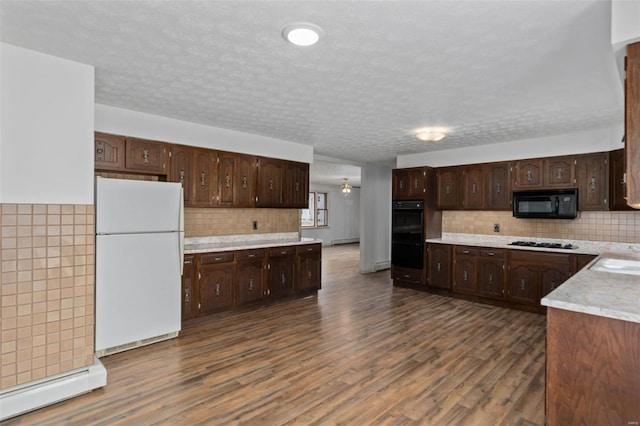 kitchen featuring dark brown cabinetry, black appliances, a baseboard heating unit, and dark wood-type flooring