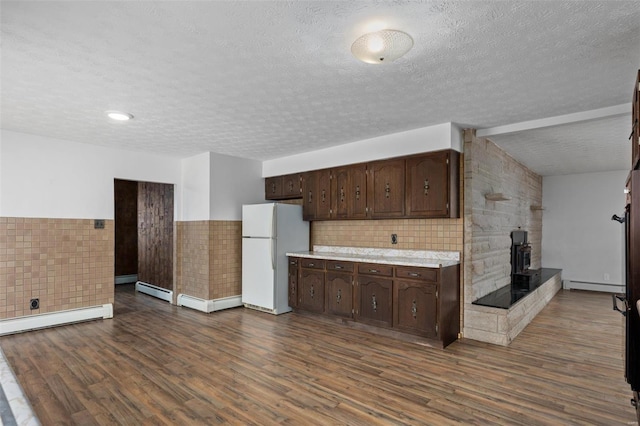 kitchen featuring dark wood-style flooring, light countertops, a baseboard heating unit, freestanding refrigerator, and dark brown cabinets