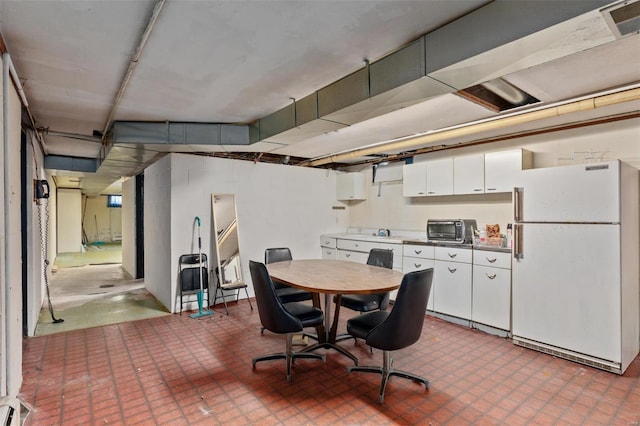 kitchen with freestanding refrigerator, a toaster, and white cabinetry