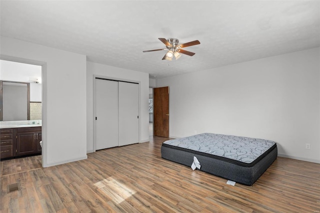 bedroom featuring a textured ceiling, a closet, wood finished floors, and baseboards