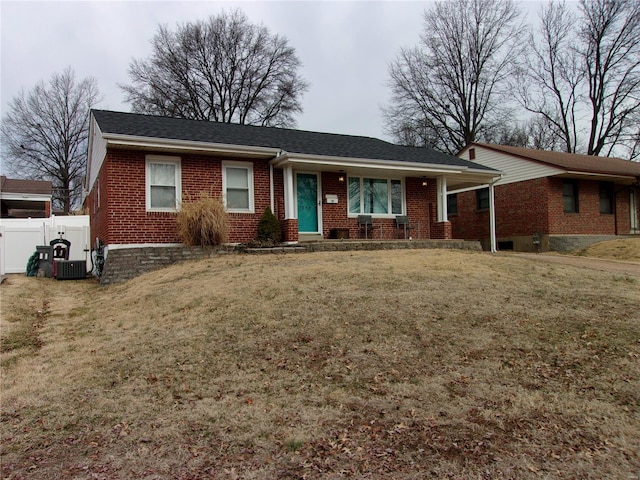 ranch-style home featuring brick siding, fence, a front lawn, and roof with shingles