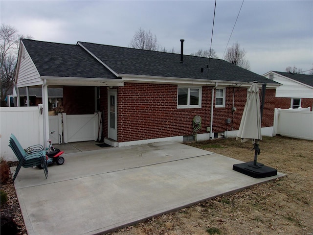 back of property featuring a patio area, a shingled roof, fence, and brick siding