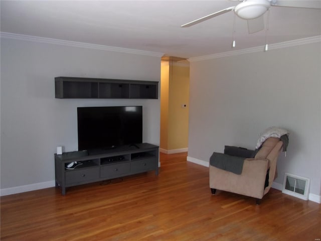 sitting room with ceiling fan, wood finished floors, visible vents, baseboards, and crown molding