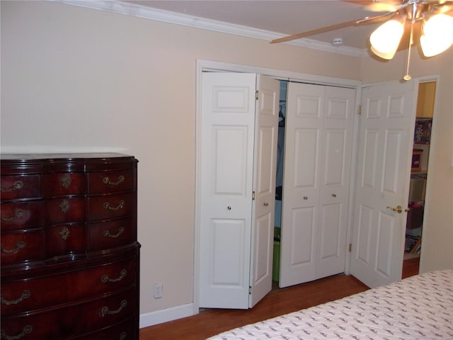 bedroom with baseboards, a ceiling fan, dark wood-style floors, crown molding, and a closet