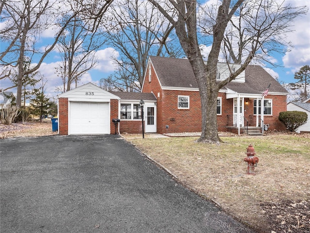 view of front of property featuring brick siding, roof with shingles, an attached garage, and aphalt driveway