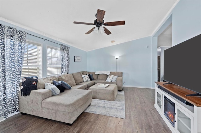 living room featuring lofted ceiling, visible vents, a ceiling fan, wood finished floors, and baseboards