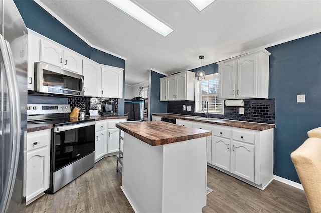 kitchen featuring wood counters, white cabinetry, appliances with stainless steel finishes, a center island, and dark wood-style floors