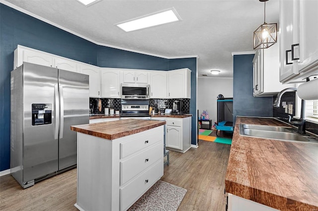 kitchen with appliances with stainless steel finishes, a sink, wood counters, and light wood-style floors