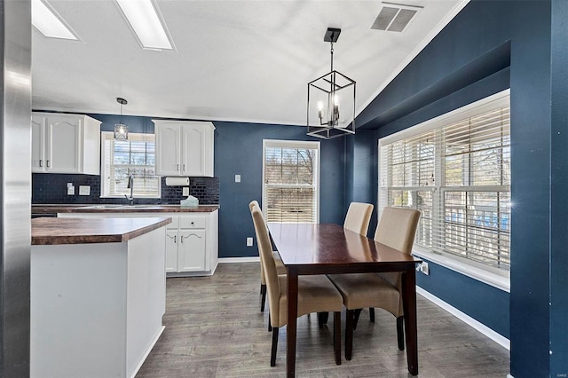 dining room with a wealth of natural light, visible vents, dark wood finished floors, and a skylight