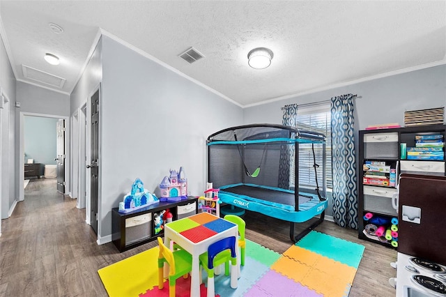 bedroom with attic access, crown molding, visible vents, and wood finished floors