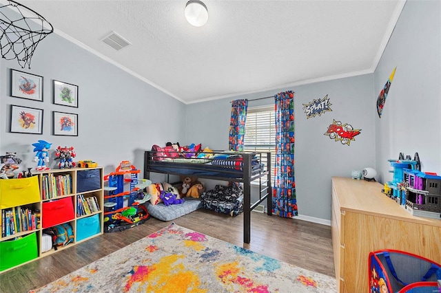 bedroom featuring baseboards, visible vents, wood finished floors, crown molding, and a textured ceiling