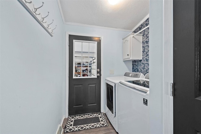 clothes washing area with a textured ceiling, washing machine and dryer, wood finished floors, ornamental molding, and cabinet space