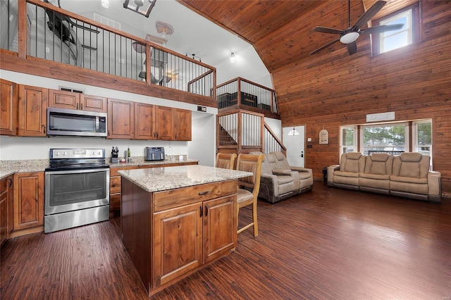 kitchen with brown cabinets, appliances with stainless steel finishes, open floor plan, and dark wood-type flooring