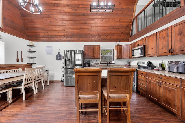 kitchen featuring high vaulted ceiling, dark wood-style flooring, a kitchen island, appliances with stainless steel finishes, and an inviting chandelier