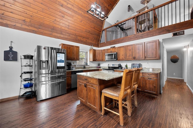 kitchen with baseboards, dark wood-style floors, a center island, stainless steel appliances, and a kitchen bar