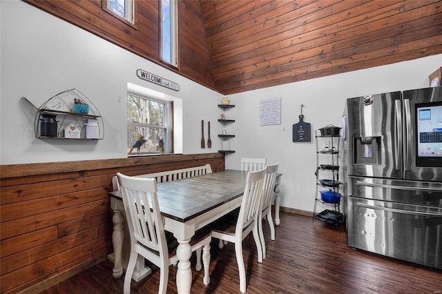 dining space with a towering ceiling, dark wood-style floors, and baseboards