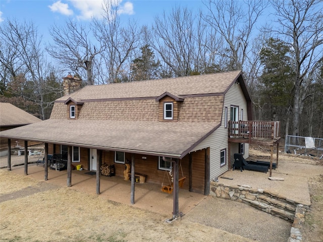 view of front of home featuring roof with shingles, a chimney, a gambrel roof, a patio area, and a deck