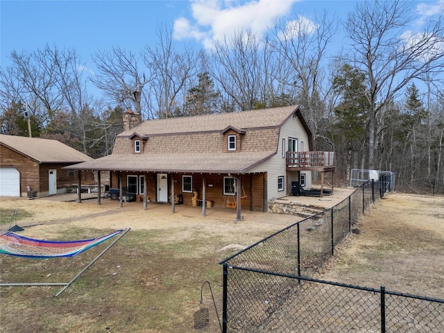 exterior space with roof with shingles, a patio, a chimney, a gambrel roof, and fence