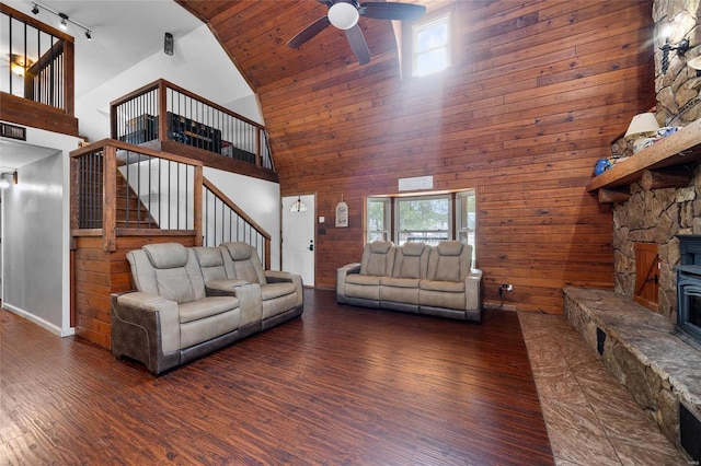 living area featuring wood walls, ceiling fan, wood finished floors, high vaulted ceiling, and stairs