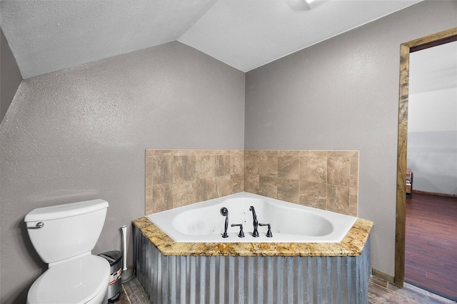 bathroom with lofted ceiling, a tub with jets, and toilet