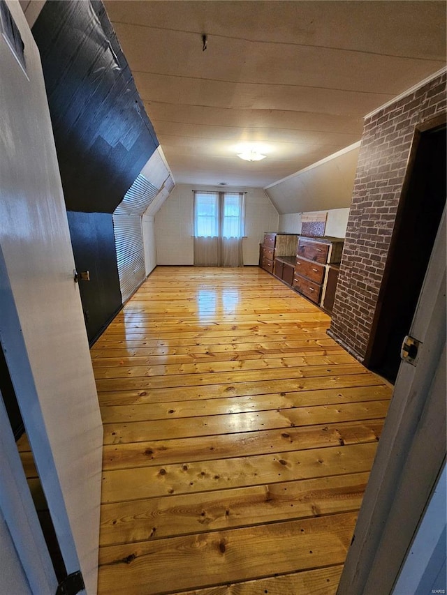 bonus room featuring lofted ceiling, brick wall, and hardwood / wood-style floors