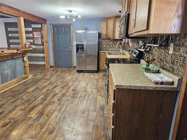 kitchen featuring decorative backsplash, brown cabinets, stainless steel appliances, light wood-type flooring, and a sink